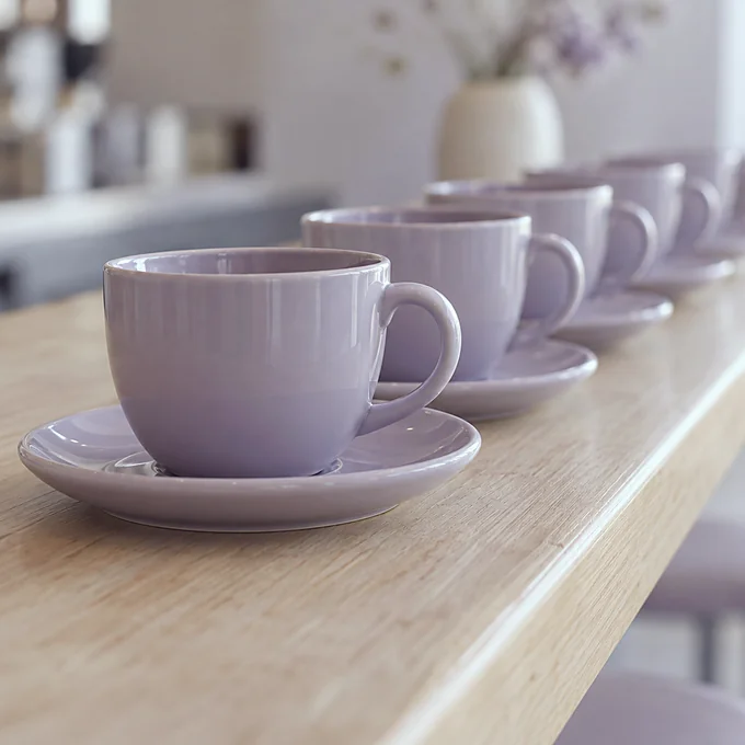 Deretan cangkir kopi ungu muda di meja bar
