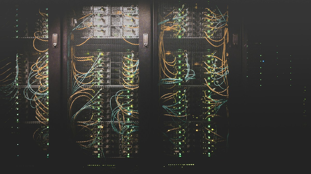 Koridor rak server datacenter modern dengan indikator jaringan aktif dan infrastruktur cloud terisolasi